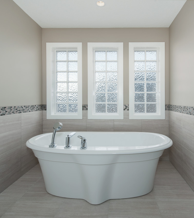 Freestanding bathtub - large transitional master gray tile and porcelain tile porcelain tile freestanding bathtub idea in Calgary with an undermount sink, granite countertops, dark wood cabinets and beige walls