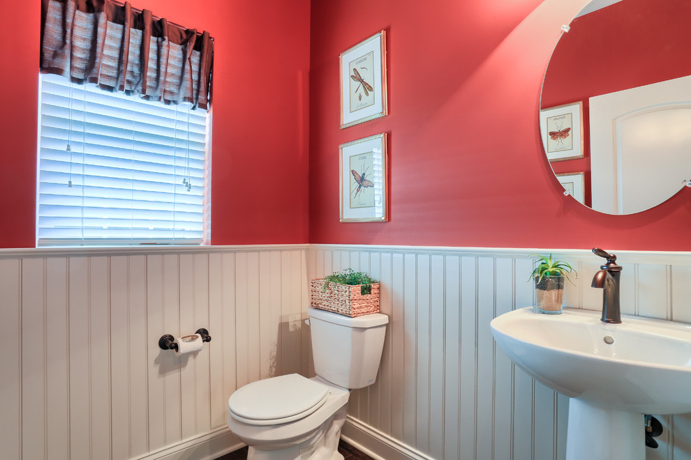 Photo of a small traditional 3/4 bathroom in Other with a pedestal sink, a two-piece toilet, red walls and dark hardwood floors.