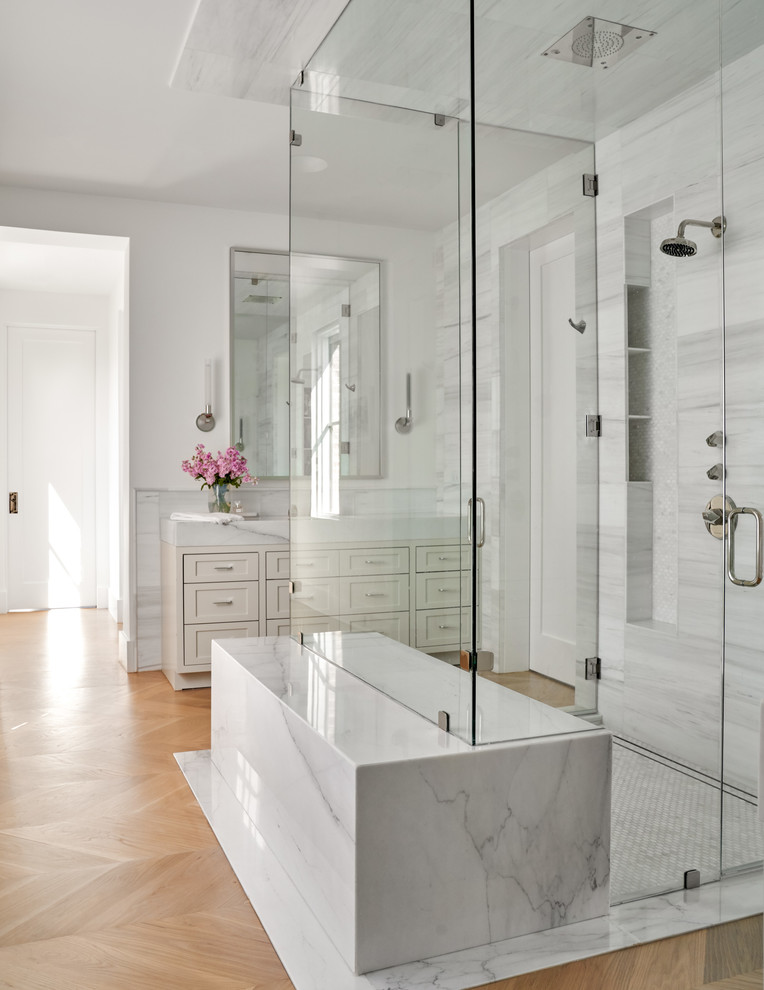 Inspiration for a mid-sized transitional master bathroom in Dallas with shaker cabinets, beige cabinets, a curbless shower, gray tile, white tile, white walls, light hardwood floors, brown floor, a hinged shower door, white benchtops, a freestanding tub, porcelain tile and marble benchtops.