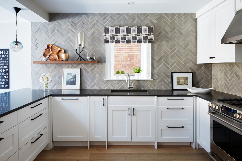 Mid-sized transitional u-shaped kitchen in Toronto with a single-bowl sink, shaker cabinets, quartzite benchtops, grey splashback, stainless steel appliances, light hardwood floors, white cabinets and a peninsula.