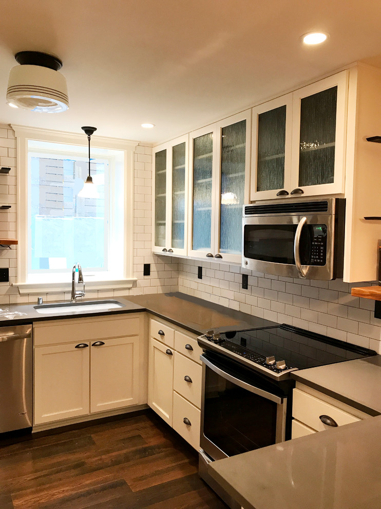 Inspiration for a small traditional u-shaped open plan kitchen in Seattle with an undermount sink, shaker cabinets, white cabinets, quartz benchtops, white splashback, ceramic splashback, stainless steel appliances, dark hardwood floors, a peninsula and brown floor.