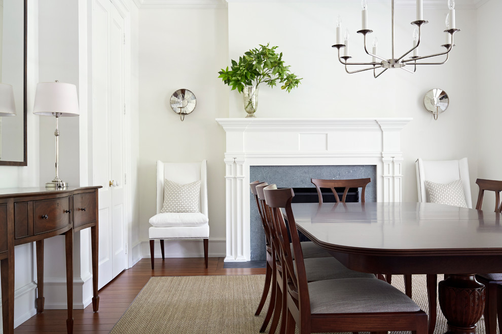 Example of a cottage medium tone wood floor dining room design with white walls and a standard fireplace