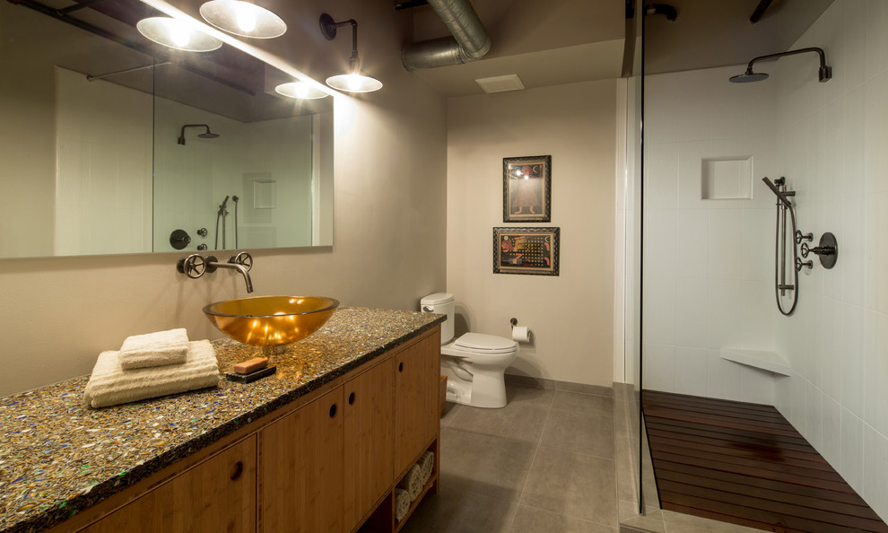 This is an example of a mid-sized industrial master bathroom in Portland with a vessel sink, beaded inset cabinets, medium wood cabinets, terrazzo benchtops, an open shower, a two-piece toilet, white tile, porcelain tile, beige walls and porcelain floors.