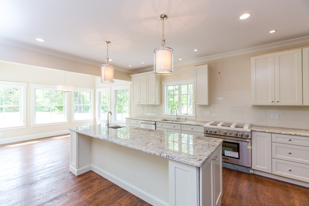 This is an example of a large transitional l-shaped open plan kitchen in Boston with recessed-panel cabinets, white cabinets, stainless steel appliances, medium hardwood floors and with island.
