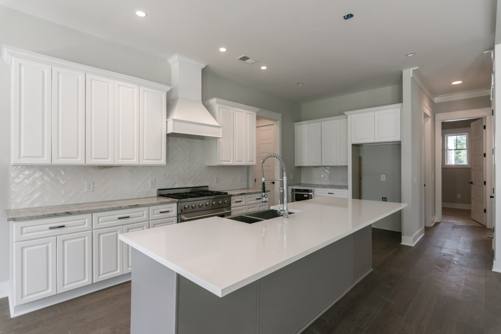 Design ideas for a large country l-shaped open plan kitchen in Nashville with a farmhouse sink, raised-panel cabinets, white cabinets, quartzite benchtops, grey splashback, ceramic splashback, stainless steel appliances, vinyl floors, with island, brown floor and grey benchtop.