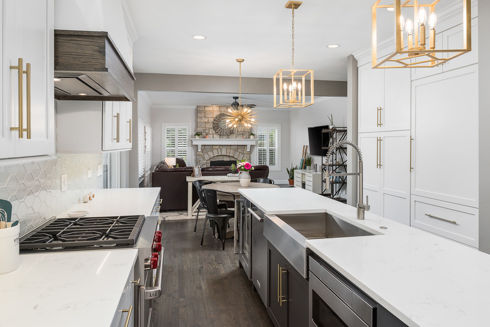 Photo of a mid-sized transitional single-wall open plan kitchen in Chicago with white cabinets, quartz benchtops, white splashback, stainless steel appliances, dark hardwood floors, with island, brown floor, white benchtop, a farmhouse sink, shaker cabinets and glass tile splashback.