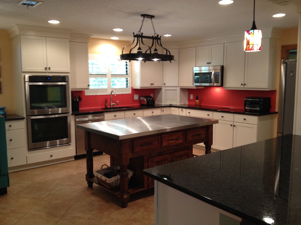 Transitional u-shaped eat-in kitchen in Jacksonville with an undermount sink, shaker cabinets, white cabinets, granite benchtops, orange splashback and stainless steel appliances.