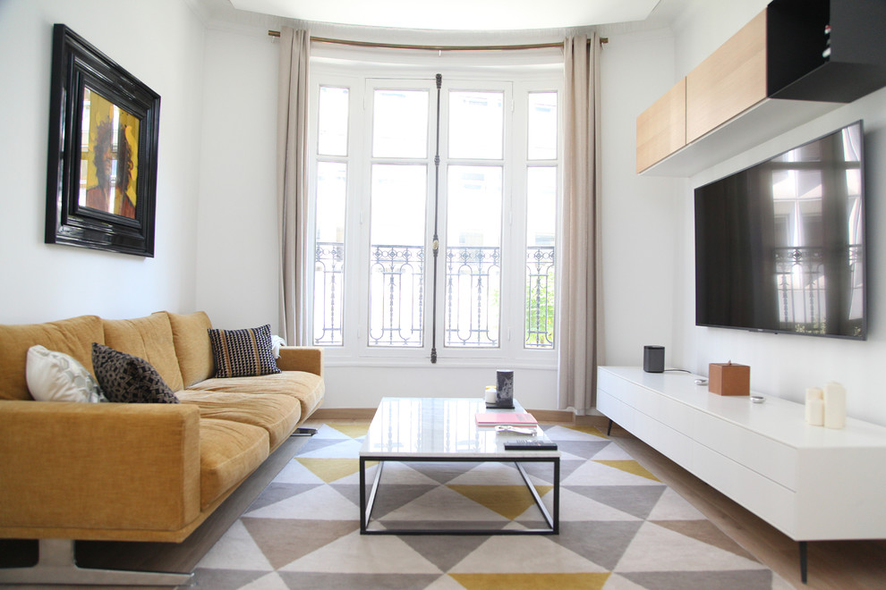 Inspiration for a small contemporary open concept living room in Paris with white walls, light hardwood floors and a wall-mounted tv.