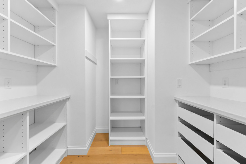 Example of a mid-sized transitional u-shaped light wood floor kitchen pantry design with white cabinets, a side-by-side washer/dryer, an integrated sink, recessed-panel cabinets, stainless steel appliances and an island