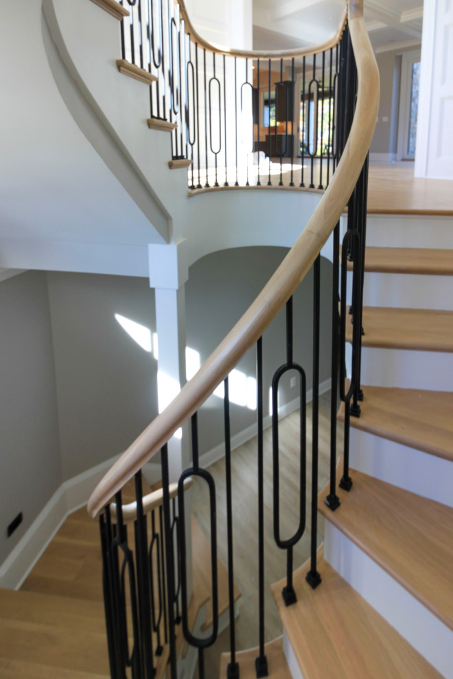 Idées déco pour un très grand escalier courbe classique avec des marches en bois, des contremarches en bois, un garde-corps en matériaux mixtes et boiseries.