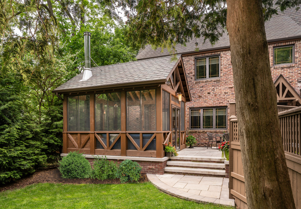 Inspiration for a small traditional backyard screened-in verandah in Detroit with natural stone pavers and a roof extension.