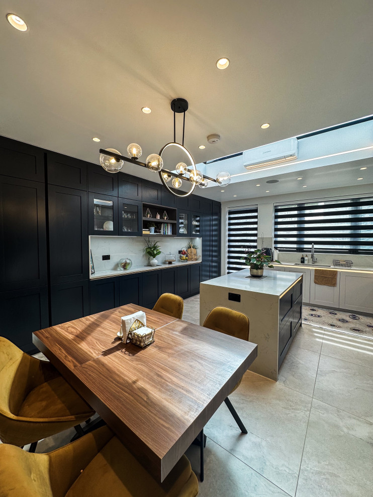 Inspiration for a large traditional l-shaped kitchen in London with a built-in sink, shaker cabinets, blue cabinets, quartz worktops, white splashback, engineered quartz splashback, integrated appliances, porcelain flooring, an island, beige floors, white worktops and feature lighting.