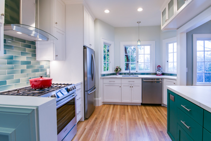 Photo of an arts and crafts kitchen in San Francisco with a single-bowl sink, raised-panel cabinets, blue cabinets, blue splashback, subway tile splashback, stainless steel appliances, white benchtop and with island.