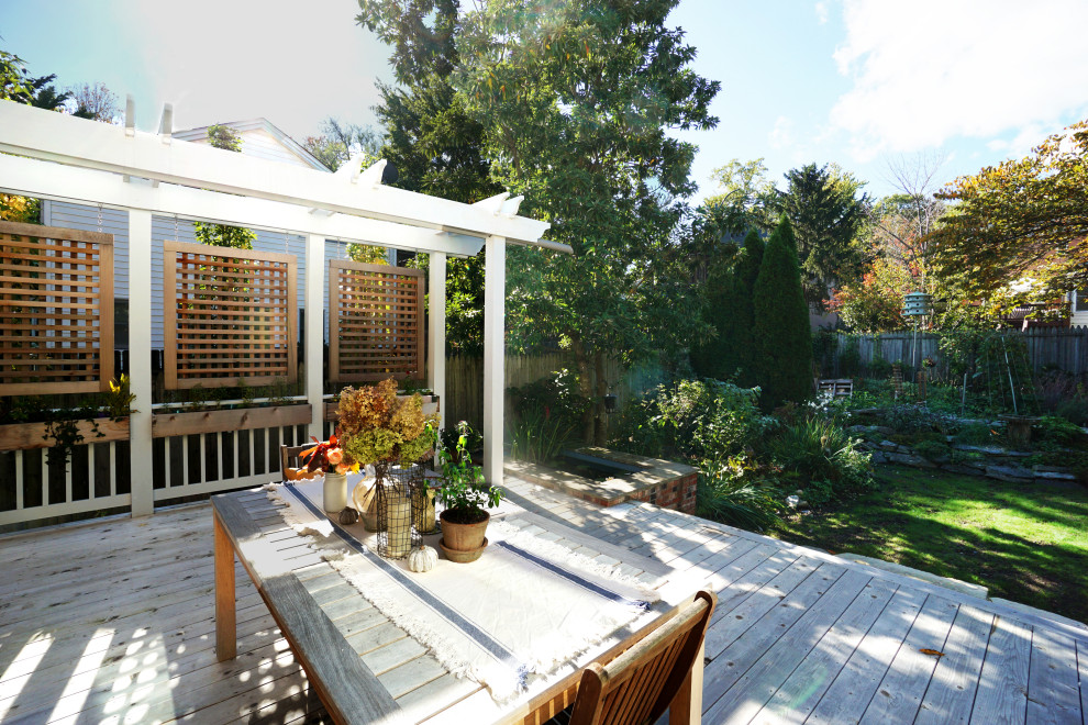 Example of a mid-sized transitional backyard ground level privacy and mixed material railing deck design in DC Metro with a pergola