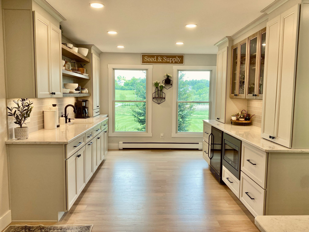 This is an example of a farmhouse kitchen in Philadelphia with a belfast sink, shaker cabinets, white cabinets, engineered stone countertops, an island and white worktops.
