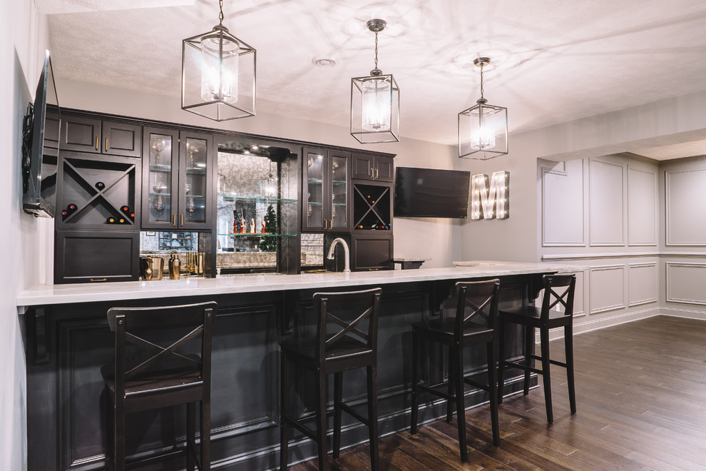 Large transitional galley dark wood floor seated home bar photo with an undermount sink, recessed-panel cabinets, marble countertops, black cabinets and mirror backsplash