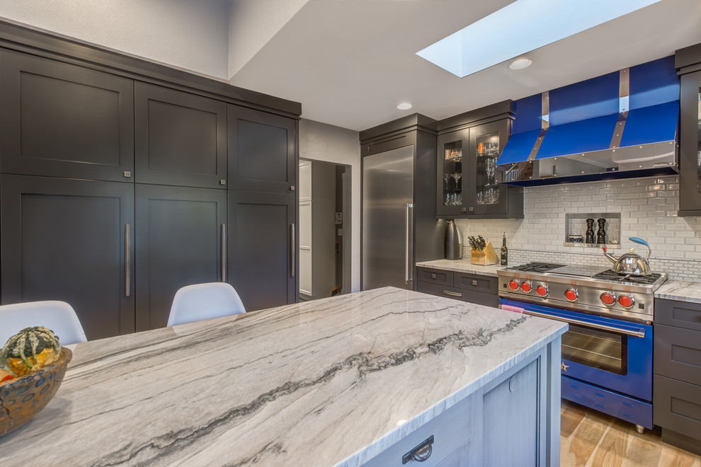 Large transitional u-shaped light wood floor eat-in kitchen photo in Denver with a farmhouse sink, recessed-panel cabinets, gray cabinets, quartzite countertops, blue backsplash, ceramic backsplash, stainless steel appliances and an island