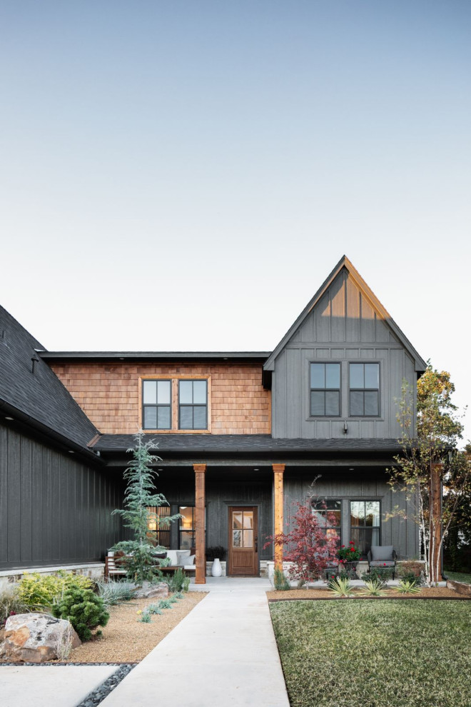 Large transitional two-storey black house exterior in Oklahoma City with wood siding, a gable roof and a shingle roof.