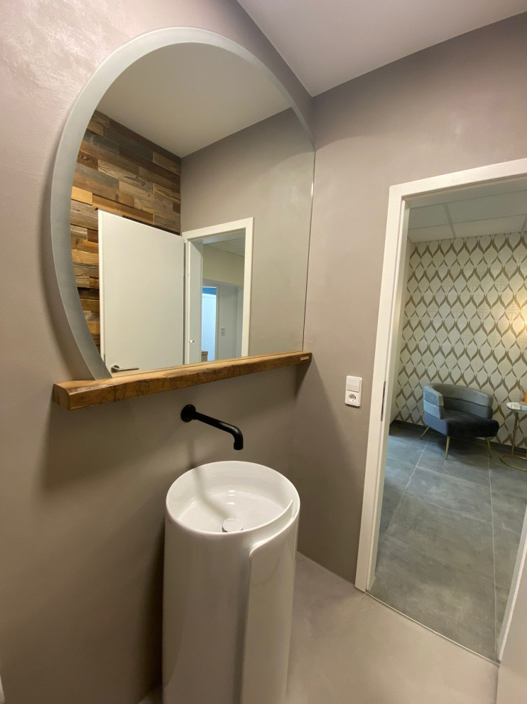 Foto på ett litet funkis brun en-suite badrum, med grå skåp, en toalettstol med separat cisternkåpa, grå väggar, betonggolv, ett piedestal handfat, bänkskiva i akrylsten och grått golv