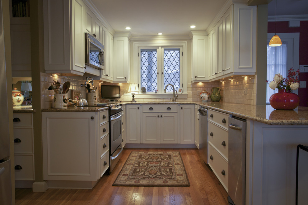 Design ideas for a traditional u-shaped kitchen in Boston with stainless steel appliances, granite benchtops, recessed-panel cabinets, white cabinets, white splashback and subway tile splashback.