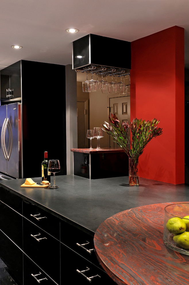 Inspiration for a mid-sized contemporary single-wall eat-in kitchen in DC Metro with an undermount sink, flat-panel cabinets, black cabinets, granite benchtops, stainless steel appliances, a peninsula, dark hardwood floors, red splashback, glass sheet splashback and grey floor.
