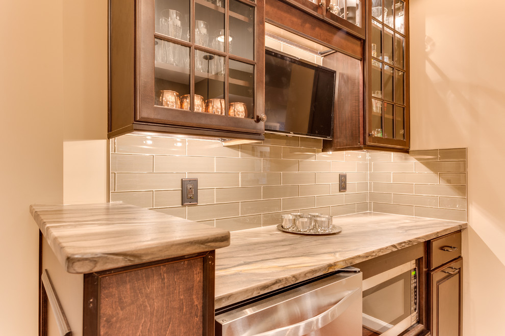 This is an example of a mid-sized traditional u-shaped wet bar in DC Metro with raised-panel cabinets, granite benchtops, glass tile splashback and medium hardwood floors.