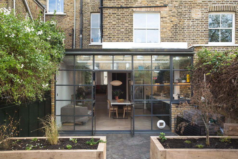 Inspiration for a large contemporary brick townhouse exterior in London with a flat roof and a mixed roof.