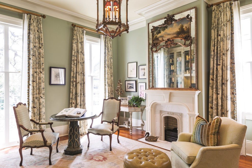 Inspiration for a large traditional living room in New Orleans with medium hardwood floors, a standard fireplace, a stone fireplace surround, no tv, brown floor, a library and green walls.