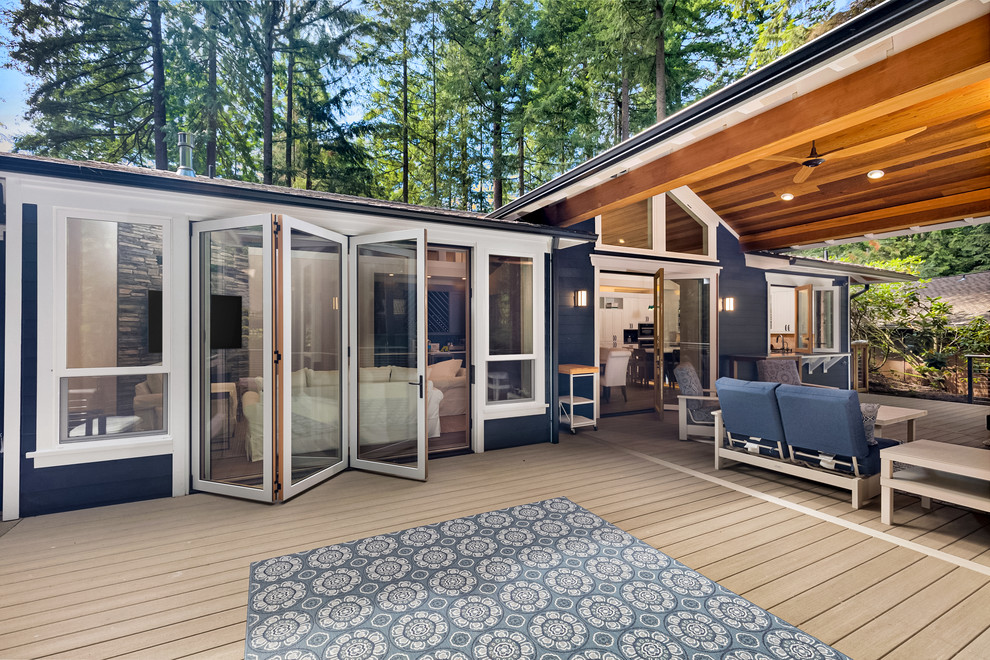 This is an example of a large arts and crafts backyard deck in Seattle with an outdoor kitchen and a roof extension.