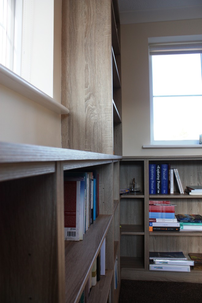 This is an example of a mid-sized contemporary study room in Kent with beige walls, carpet, a freestanding desk and brown floor.