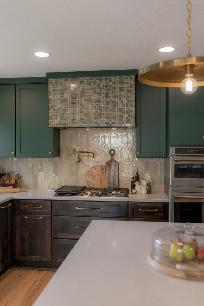 Example of a mid-sized transitional l-shaped light wood floor and brown floor eat-in kitchen design with an undermount sink, recessed-panel cabinets, green cabinets, quartz countertops, beige backsplash, terra-cotta backsplash, stainless steel appliances, two islands and beige countertops