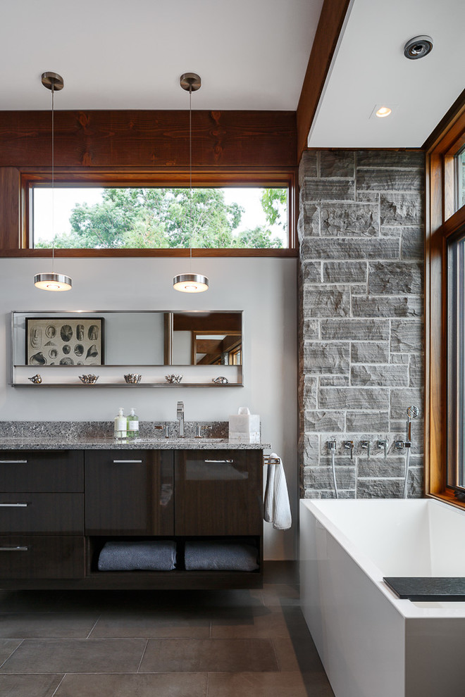 Mid-sized contemporary master bathroom in Ottawa with a freestanding tub, gray tile, white walls, flat-panel cabinets, dark wood cabinets, a two-piece toilet, stone tile, an undermount sink, engineered quartz benchtops, grey floor and grey benchtops.