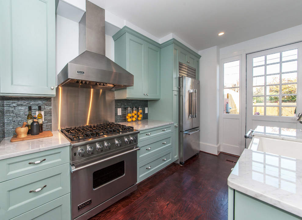 Photo of a transitional galley kitchen in San Francisco with a farmhouse sink, recessed-panel cabinets, green cabinets, metallic splashback and stainless steel appliances.