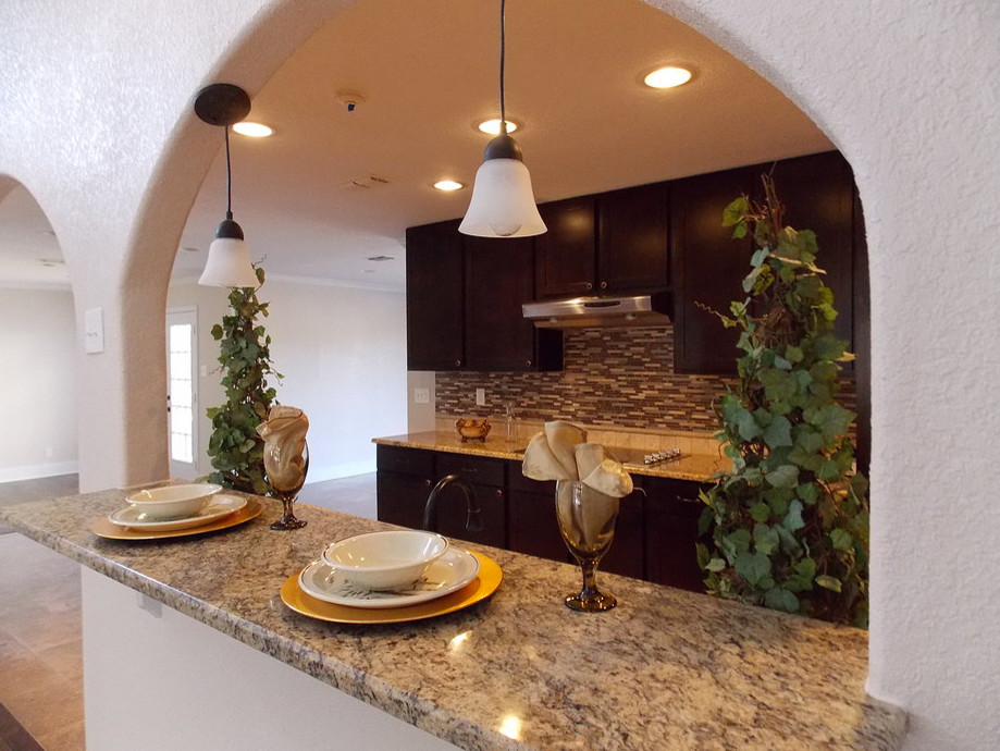 Inspiration for a large traditional galley eat-in kitchen in Austin with an undermount sink, flat-panel cabinets, dark wood cabinets, granite benchtops, multi-coloured splashback, glass tile splashback, stainless steel appliances, ceramic floors and no island.