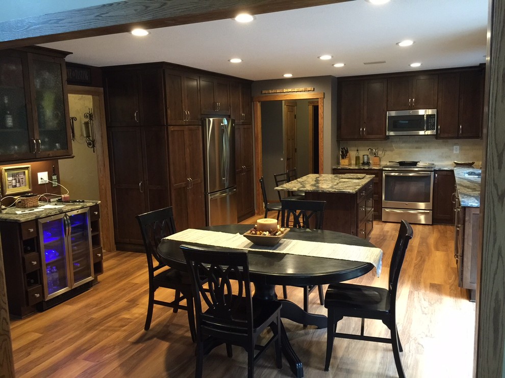 Inspiration for a large medium tone wood floor kitchen remodel in Minneapolis with an undermount sink, dark wood cabinets, white backsplash, stainless steel appliances and an island