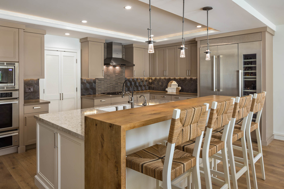 Transitional l-shaped medium tone wood floor and brown floor kitchen photo in San Francisco with an undermount sink, recessed-panel cabinets, gray backsplash, stainless steel appliances, an island, gray countertops and beige cabinets