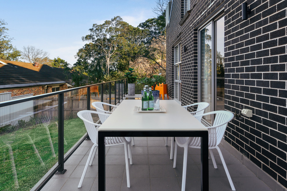Contemporary balcony in Sydney with no cover and glass railing.