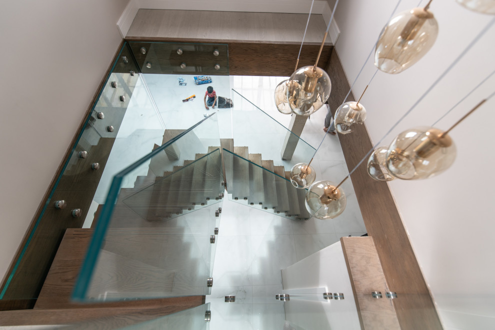 Photo of a mid-sized contemporary wood l-shaped staircase in London with open risers and glass railing.