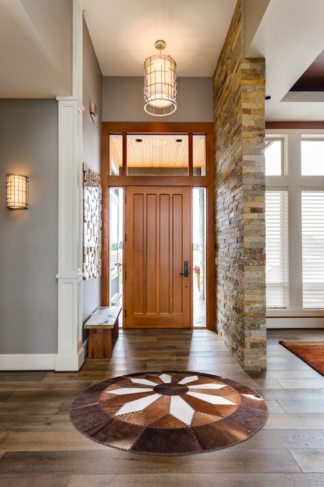 Photo of a mid-sized transitional foyer in Los Angeles with grey walls, medium hardwood floors, a single front door, a medium wood front door and brown floor.