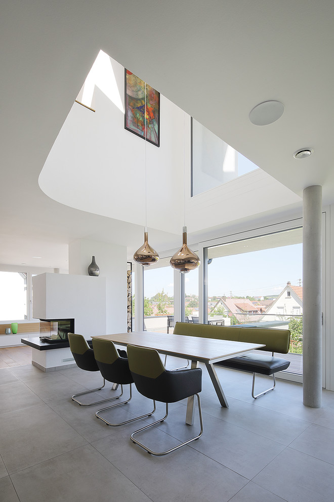 This is an example of a large contemporary open plan dining with white walls, grey floor and no fireplace.