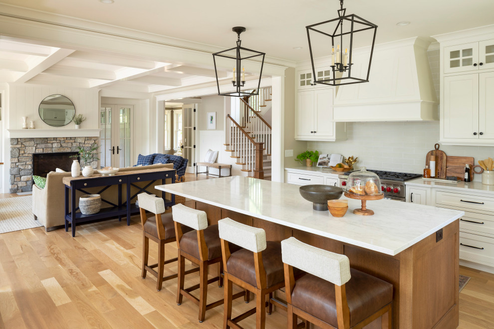 Mid-sized beach style l-shaped eat-in kitchen in Minneapolis with a farmhouse sink, beaded inset cabinets, white cabinets, quartz benchtops, beige splashback, ceramic splashback, stainless steel appliances, light hardwood floors, with island, white benchtop and coffered.