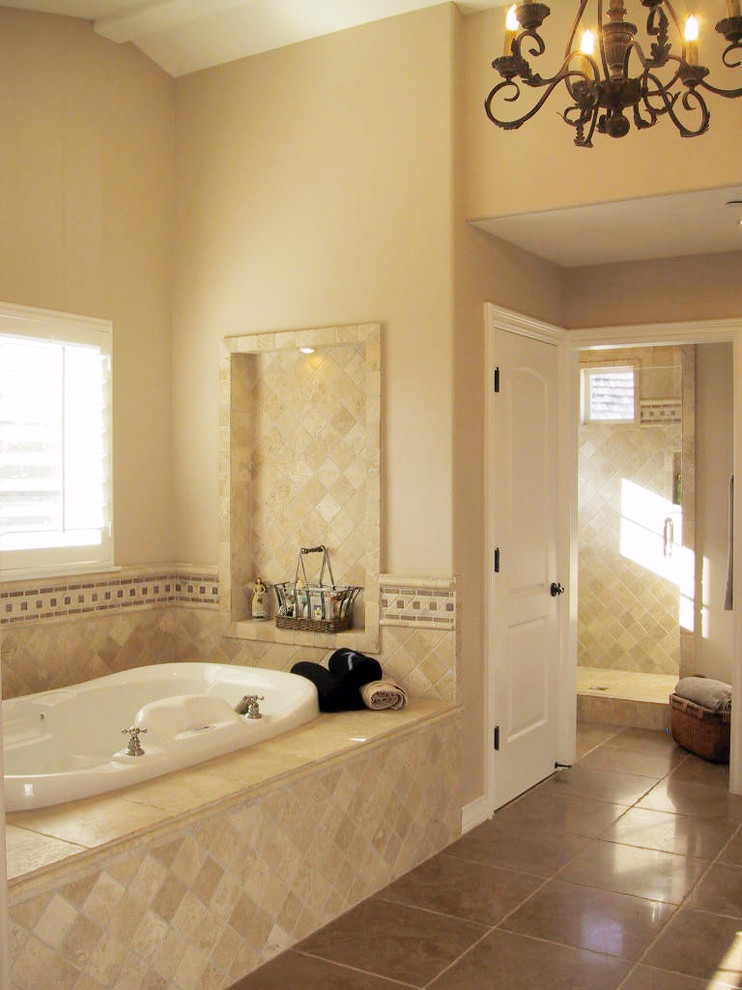 Expansive country master bathroom in Orange County with raised-panel cabinets, white cabinets, a drop-in tub, an alcove shower, a one-piece toilet, beige tile, stone tile, beige walls, limestone floors, a drop-in sink and limestone benchtops.