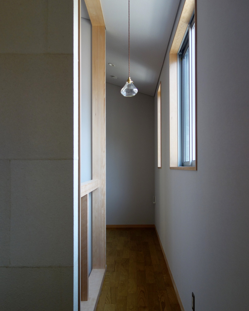 Imagen de recibidores y pasillos abovedados contemporáneos pequeños con paredes grises, suelo de contrachapado, suelo marrón y papel pintado