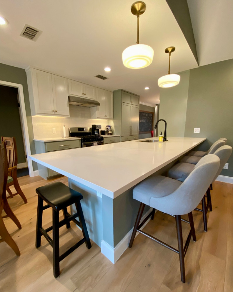 This is an example of a medium sized modern galley kitchen/diner in Austin with a built-in sink, shaker cabinets, green cabinets, quartz worktops, white splashback, ceramic splashback, stainless steel appliances, light hardwood flooring, an island, beige floors, white worktops and a wood ceiling.