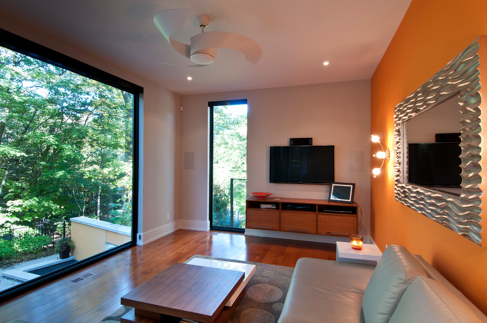 Inspiration for a mid-sized contemporary open concept family room in Toronto with orange walls, medium hardwood floors, no fireplace and a wall-mounted tv.