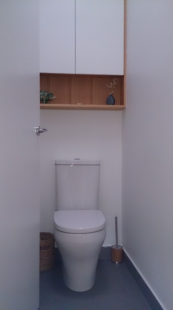 Cette photo montre un grand WC et toilettes éclectique en bois clair avec un placard à porte plane, WC à poser, un carrelage blanc, des carreaux de céramique, un mur blanc, un sol en carrelage de porcelaine, un lavabo posé et un plan de toilette en quartz modifié.