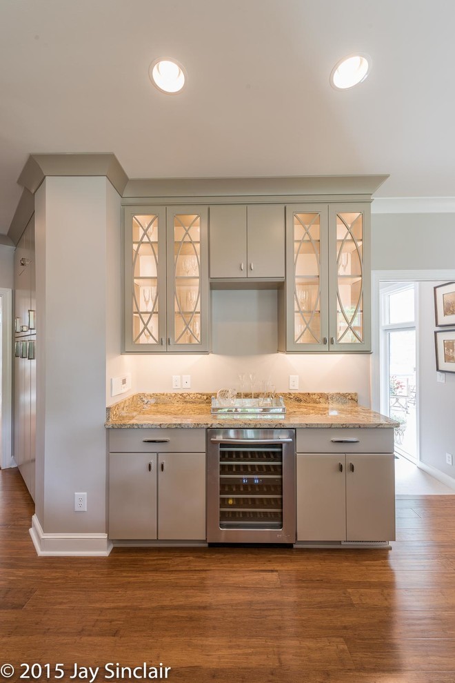 Example of a large transitional u-shaped medium tone wood floor eat-in kitchen design with flat-panel cabinets, brown cabinets, granite countertops, stainless steel appliances, an undermount sink, white backsplash, glass tile backsplash and an island