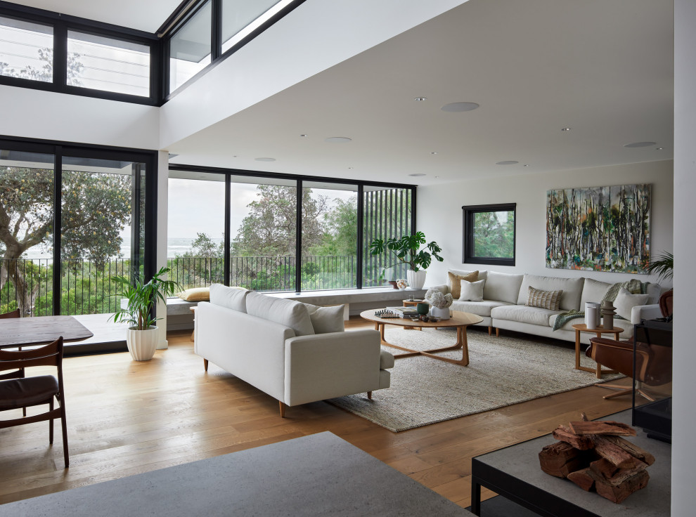 This is an example of a large contemporary open concept living room in Melbourne with white walls, medium hardwood floors, a wood stove and a metal fireplace surround.
