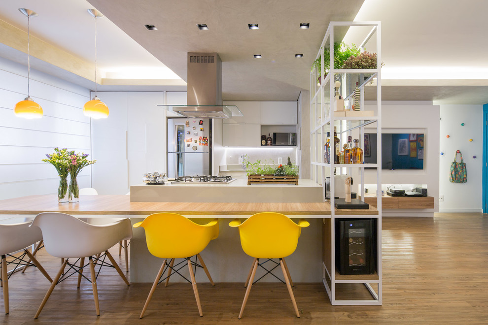 This is an example of a mid-sized contemporary galley eat-in kitchen with white cabinets, stainless steel appliances, with island, a single-bowl sink, glass-front cabinets, limestone benchtops, white splashback, cement tile splashback and vinyl floors.
