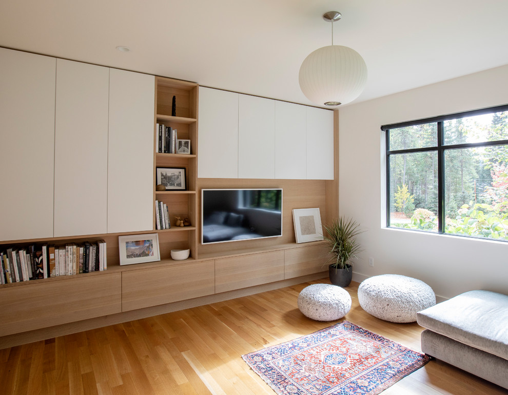 Example of a trendy medium tone wood floor and brown floor family room design in Vancouver with white walls and a wall-mounted tv